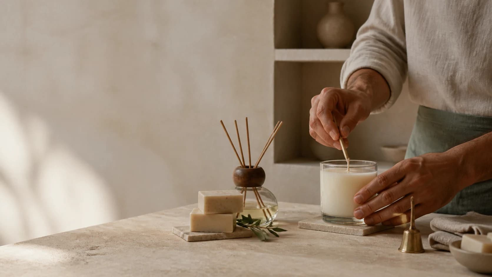An artisan's hands finishing a hand-poured candle in a warm workshop